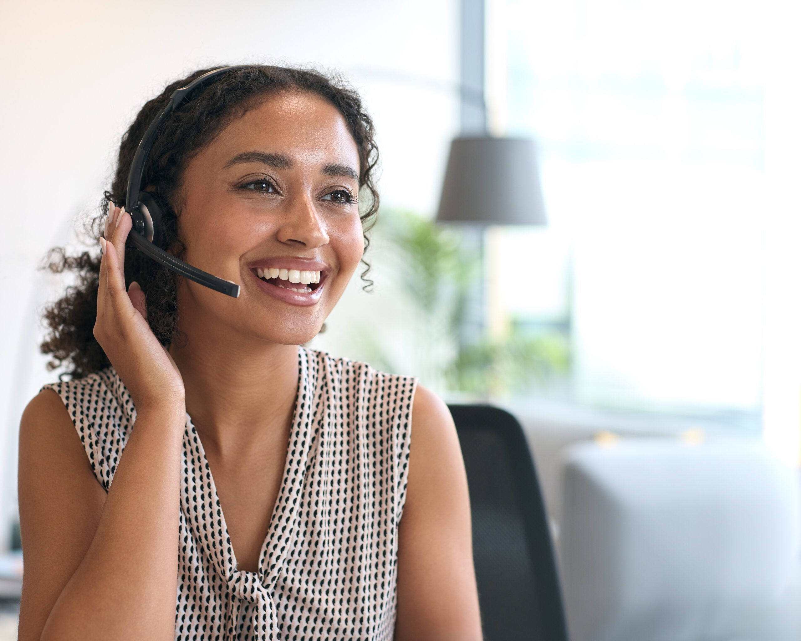 Portrait Of Woman Wearing Headset Sitting At Desk Working In Office Call Centre Team Taking Call